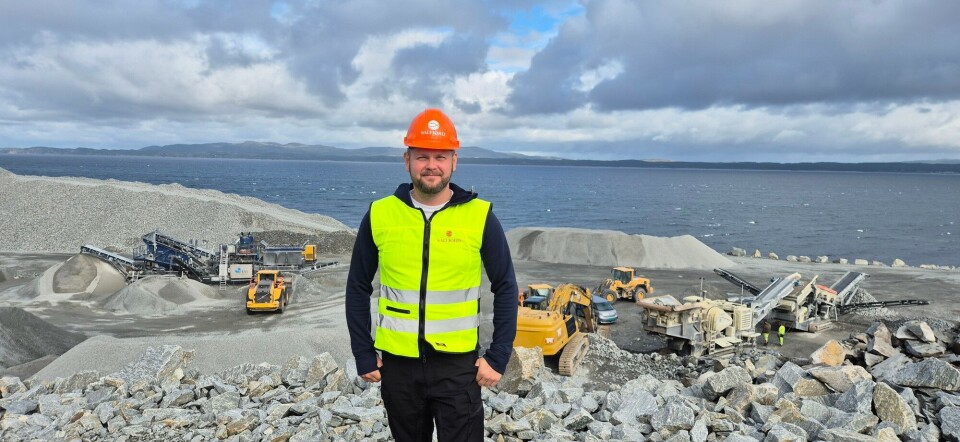 Salfjord chief operating officer Robin Fladseth with the fish farm site behind him. Rock crushing equipment is being used to convert excavated material into aggregate for construction projects.